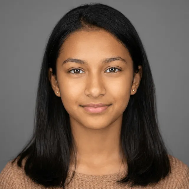 A young woman with long straight dark hair and small gold stud earrings, wearing a tan knit sweater, smiling softly at the camera.