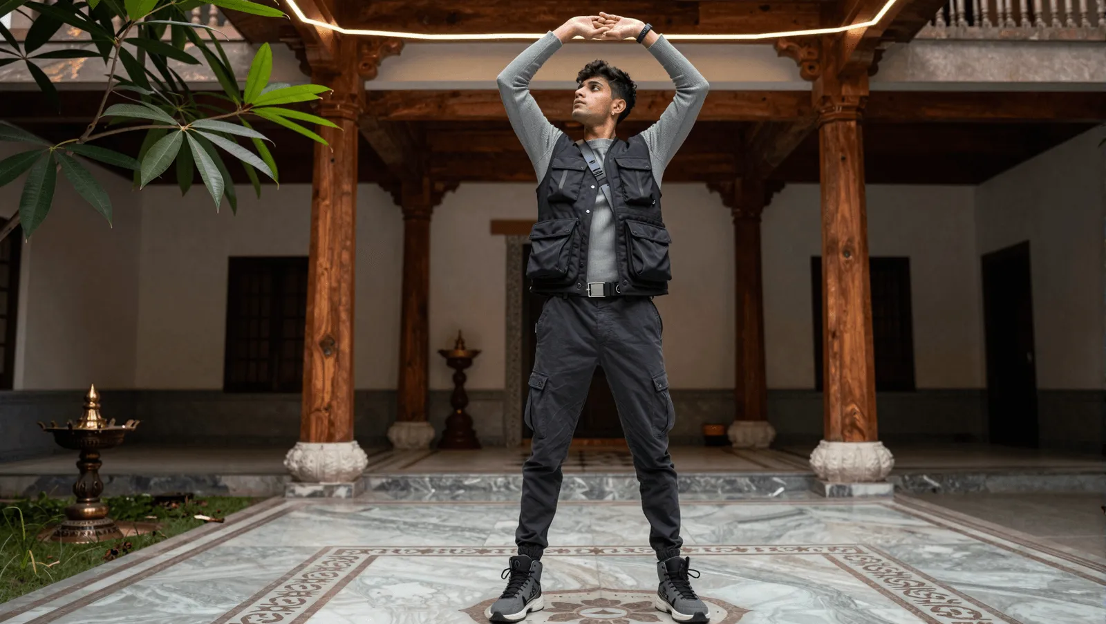 A young man in a utility vest stretching in a heritage courtyard
